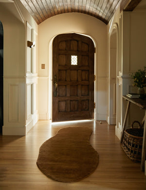 The longer Rangely Rug lays in an arched entryway in front of a large accented wooden door under an arched wooden-paneled ceiling