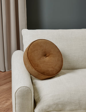 Velvet Disc amber Pillow by Sarah Sherman Samuel sits on natural linen accent chair