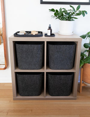 Four of The Sculpted Bin in carbon black (Set of 3) by SortJoy sit in a wooden shelf