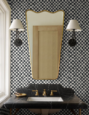 Black and ivory Checkerboard Wallpaper by Sarah Sherman Samuel is in a bathroom with black marble counter tops and a ripple golden framed mirror