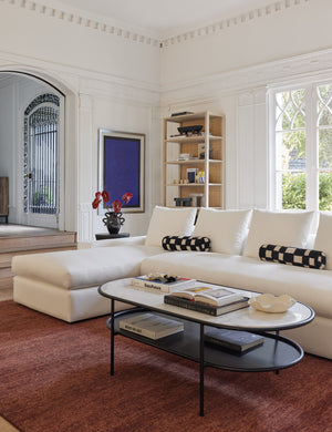 The Heritage brick rug lays in a living room under an oval coffee table and a white sectional sofa with checkerboard pillows