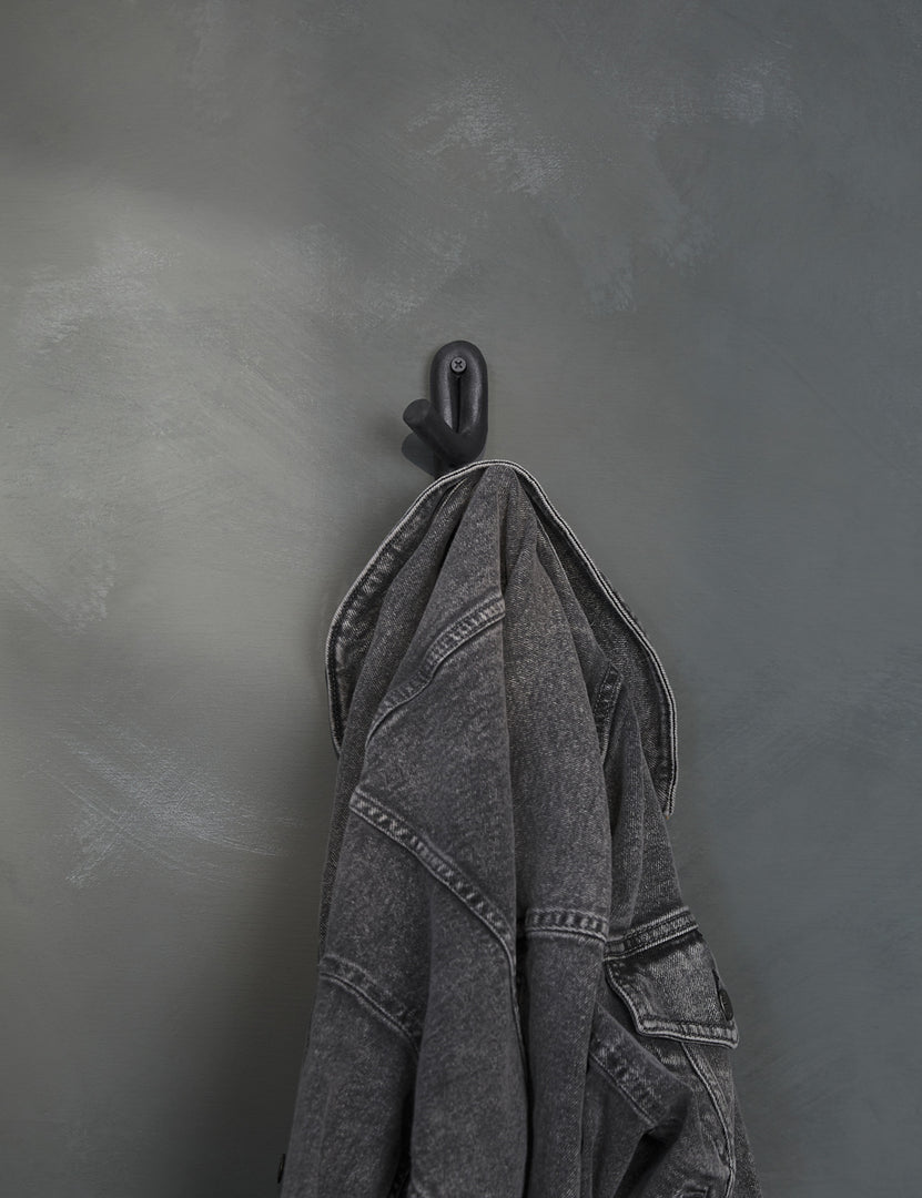 #color::black | Black Leggy Crossed Wall Hook by SIN Ceramics with a black jean jacket hanging on it