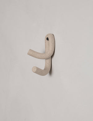 Cream speckled Leggy Crossed Wall Hook by SIN Ceramics hanging from a gray wall