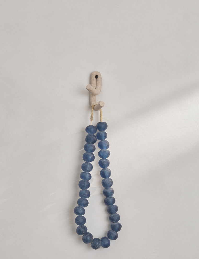 #color::speckled | Cream speckled Leggy Crossed Wall Hook by SIN Ceramics with a blue beaded necklace hanging from it