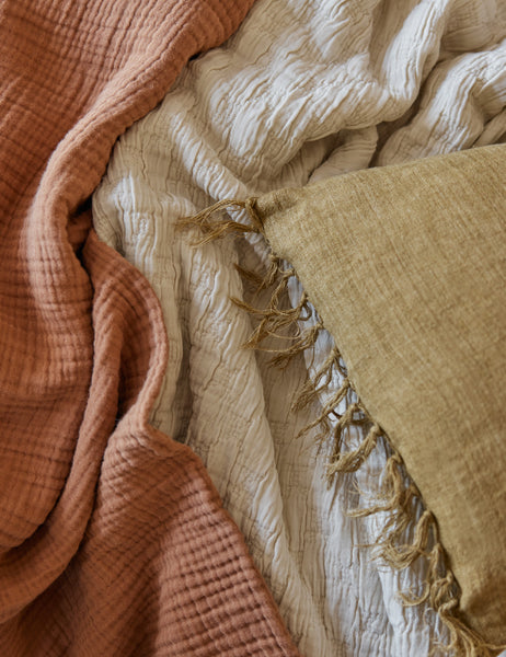 #color::greige #size::king #size::queen #size::twin | The Ojaj greige cotton matelassé coverlet by pom pom at home lays with a terracotta throw blanket and a mustard tassel pillow