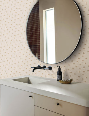 The starfish wallpaper is in a bathroom with a white sink, black hardware, and a black framed round mirror