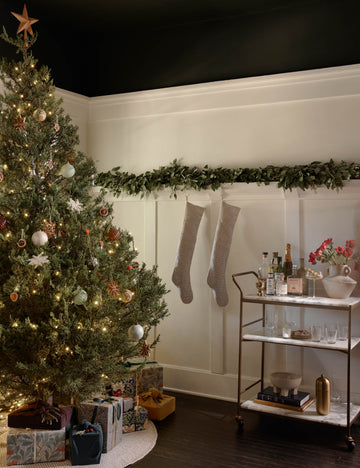 #color::antique-brass | Evander brass frame and white marble bar cart styled next to a christmas tree and railing with stockings.