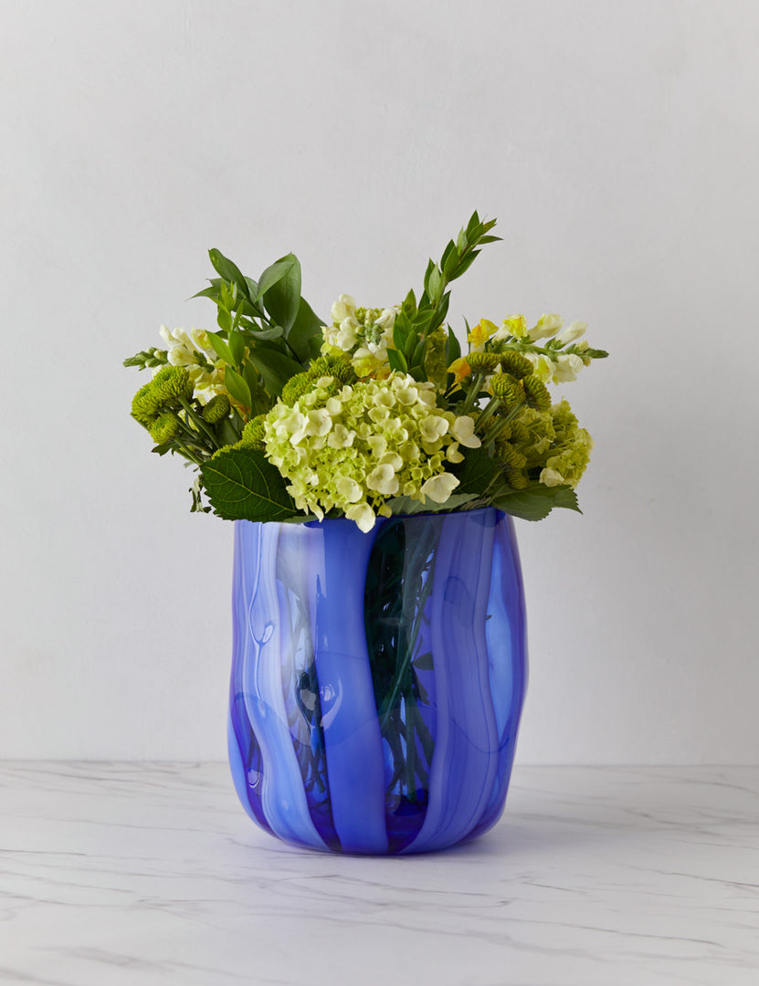 | Umi glass vase with striated wave-like vertical blue lines with flowers inside