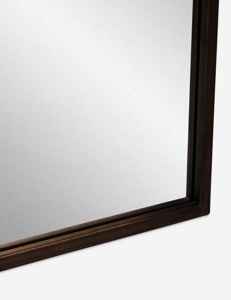 #color::oil-rubbed-bronze | Detailed shot of the bottom corner of the oil rubbed bronze metal frame on the Tulca curved standing mirror with flat bottom edge.