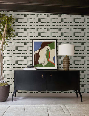The Anabella black wood console table with silver drawer pulls sits underneath a geometric wall art against black and white patterned wallpaper.