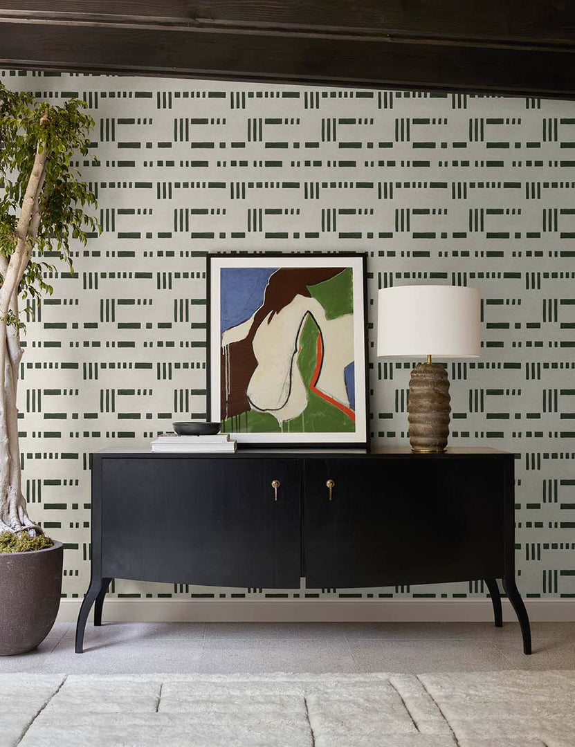 | The Anabella black wood console table with silver drawer pulls sits underneath a geometric wall art against black and white patterned wallpaper.