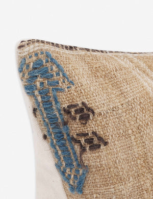 Corner of the Rica taupe lumbar throw pillow with blue, white, and black woven arrow-like designs