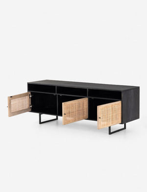 Angled view of the Hannah black mango wood media console with its three cane doors open, revealing the inner shelving.