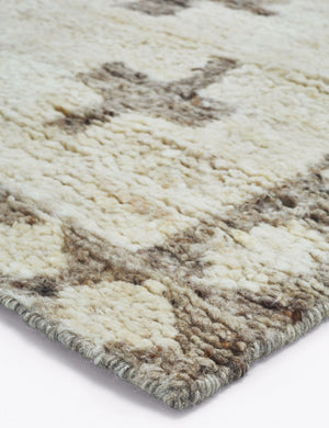 A corner of the Acoma cream and tan plus-sign patterned Moroccan area rug with diamond border.