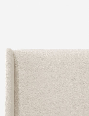 Close-up of the subtle winged headboard and trim lines on the Adara cream sherpa upholstered bed.
