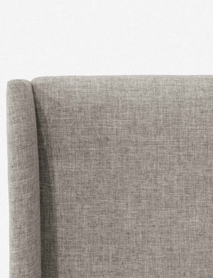 Close-up of the subtle winged headboard and trim lines on the Adara light gray linen upholstered bed.