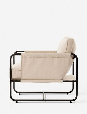Side view of the Alena accent chair with cream linen cushions and black metal frame