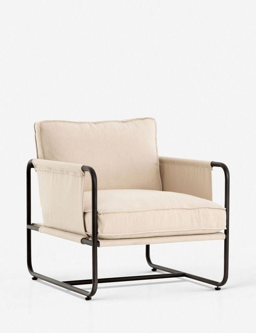 | Angled view of the Alena accent chair with cream linen cushions and black metal frame