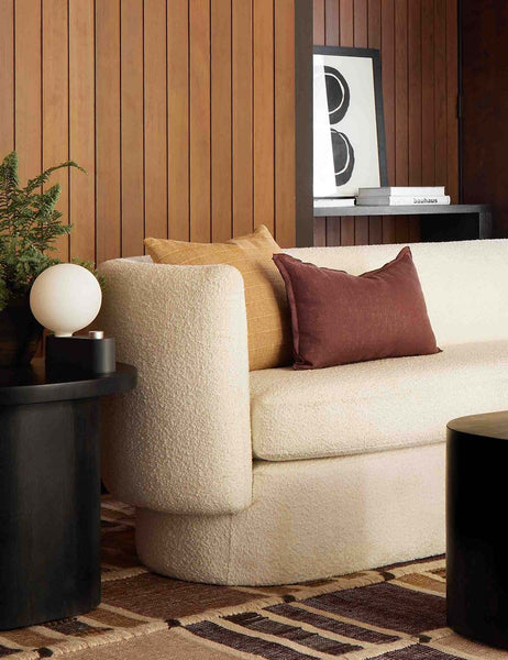 #color::aubergine #style::lumbar | The arlo aubergine lumbar pillow sits in a retro room on a cream boucle sofa