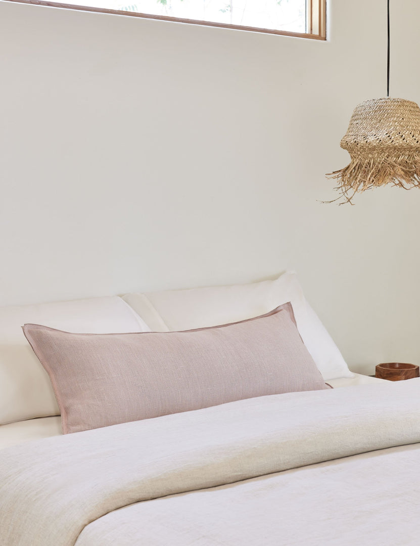 #color::greige #style::long-lumbar | The arlo Greige long lumbar pillow lays on a bed with ivory linens with a jute pendant light hanging next to it