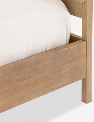 Close-up of the light wood corner of the Hannah bed with cane bed frame.