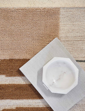 Close-up of the Benita natural toned hand-knotted floor rug by Nina Freudenberger with a book and marble octagonal bowl sitting atop it