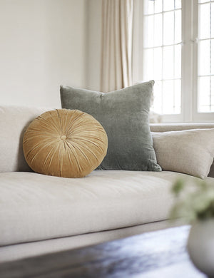 Charlotte Moss Green Square Velvet Pillow sits on a linen couch with a yellow disc velvet pillow