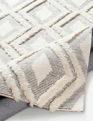 The Era wool diamond tufted geometric high-low area rug is folded over to show the back.