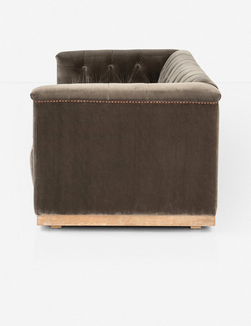| Side view of Afia tufted gray-brown velvet sofa with nailhead trim and light wood base