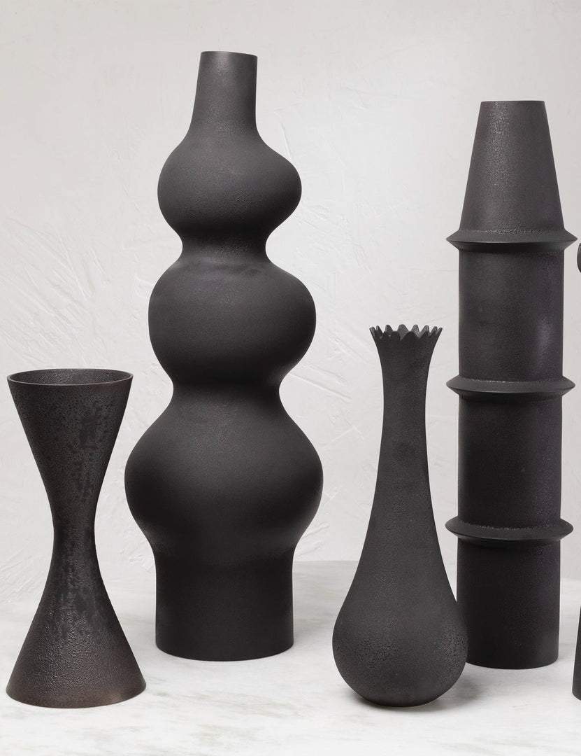 #color::matte-Black | The Lemieux et Cie Pasteur matte black geometric curved Floor Vase sits in a room with other matte black geometric floor vases