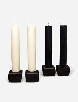 Cera Beeswax Column Candles in white and black sit in four black candle holders against a white background