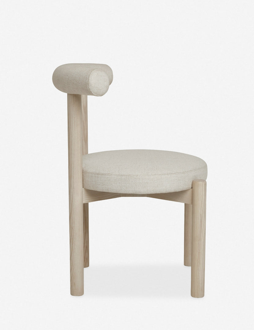 | Side view of the Dame minimalist rounded open-back dining chair with ivory upholstered seat and ash wood frame 