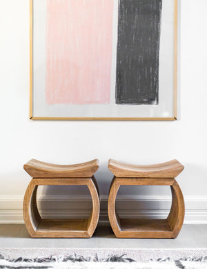 Two devlin stools sit next to each other underneath a pink and black wall art