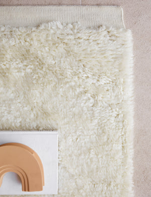 The corner of the Noa Moroccan Shag Rug under a book and beige ceramic decorative object