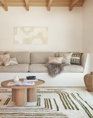The Earth Maze Moroccan Shag Rug lays in an ivory toned living room under a round coffee table and next to an inset sofa