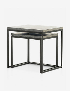 Angled view of the Ginette bluestone nesting side tables with black metal legs with the smaller table fully nested under the larger table