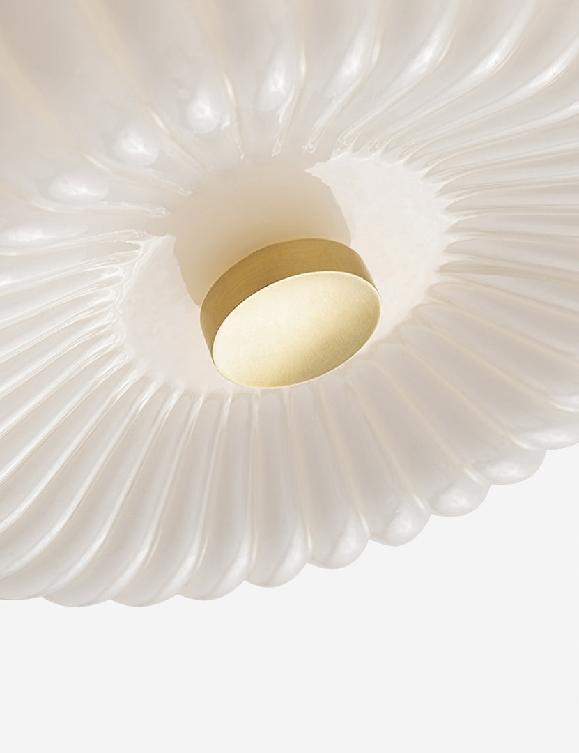 | Close-up view of the bottom of the Harissa white ribbed flush mount light with brass detail