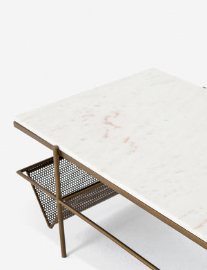 Angled upper view of the Thina rectangular marble coffee table with gold hardware and magazine shelf