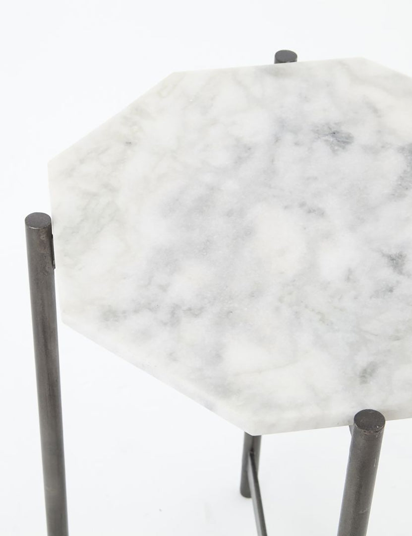 | Angled-upper view of the top of the Gianea side table with geometric white marble top and black metal frame