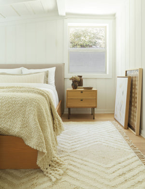 The Karma nightstand is in a bedroom with a natural linen framed bed, a chevron rug, and a bright window