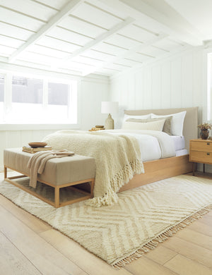The Grasmere natural stripe linen wooden bench sits at the end of a neutral-toned bed atop a diamond patterned rug