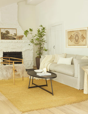 The Norala solid white handmade lumbar throw pillow sits on a natural linen sofa next to an oval coffee table