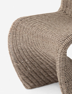 Close-up of the scooped base on the Manila wicker weave beige indoor and outdoor dining chair