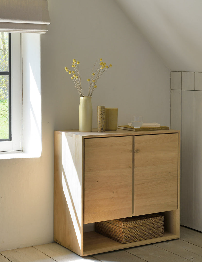 | The Lark 2-Door Sideboard sits in an attic space with a vase and book atop it