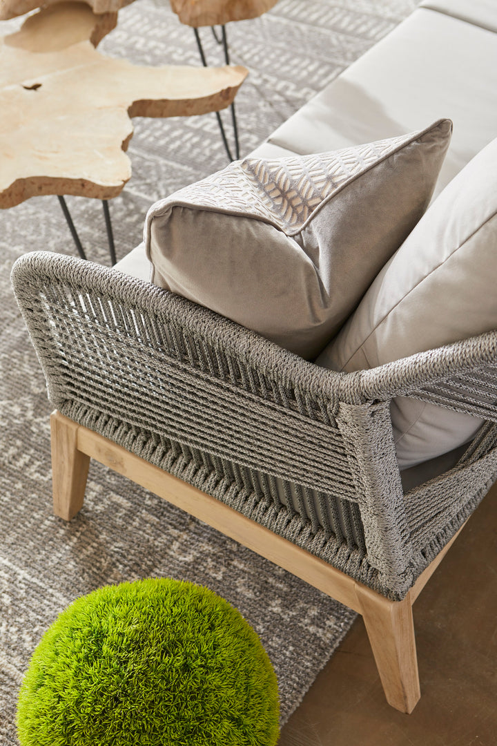 | The London Indoor / Outdoor Sofa sits atop a patterned gray rug next to two organic-shaped wooden coffee tables