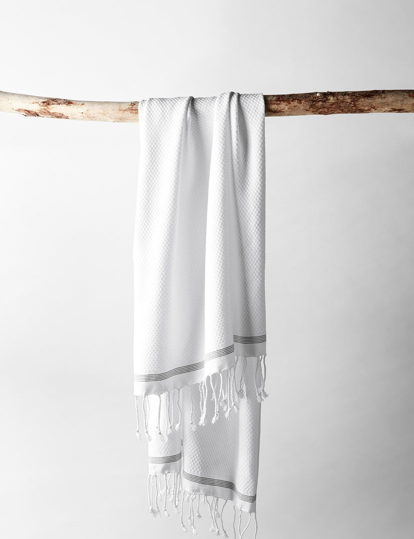 #color::white | The Mediterranean Turkish Cotton white Guest Towel by Coyuchi with tasseled ends hangs off a branch