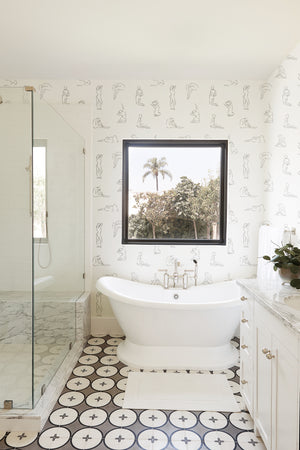The Minimalist white and black nude wallpaper is in a bathroom with patterned floors, a white bath tub, and a sink with marble counter tops