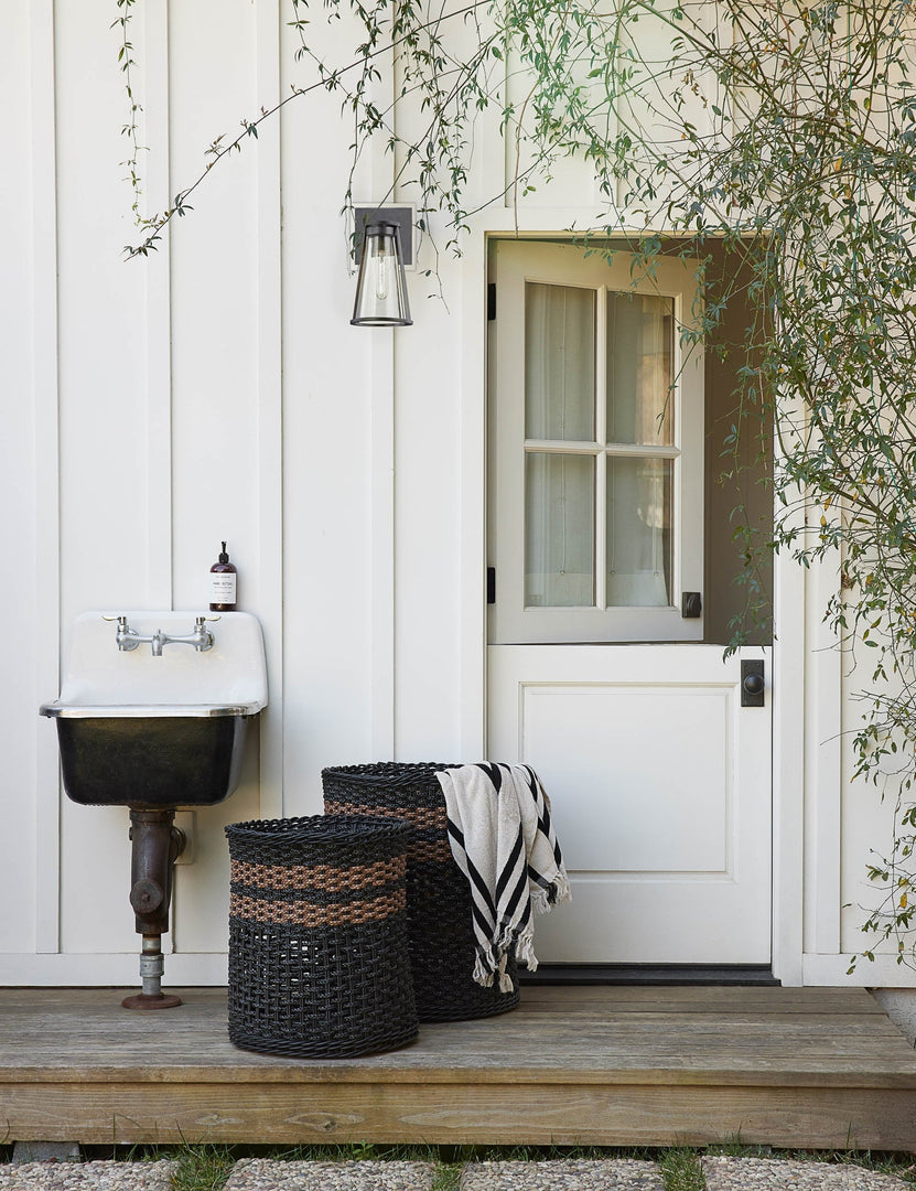#color::vintage-black-stripe #style::vintage-black-stripe | Black and white striped Beach Towel by Business & Pleasure Co hangs from a black woven basket next to an outdoor sink and dutch door