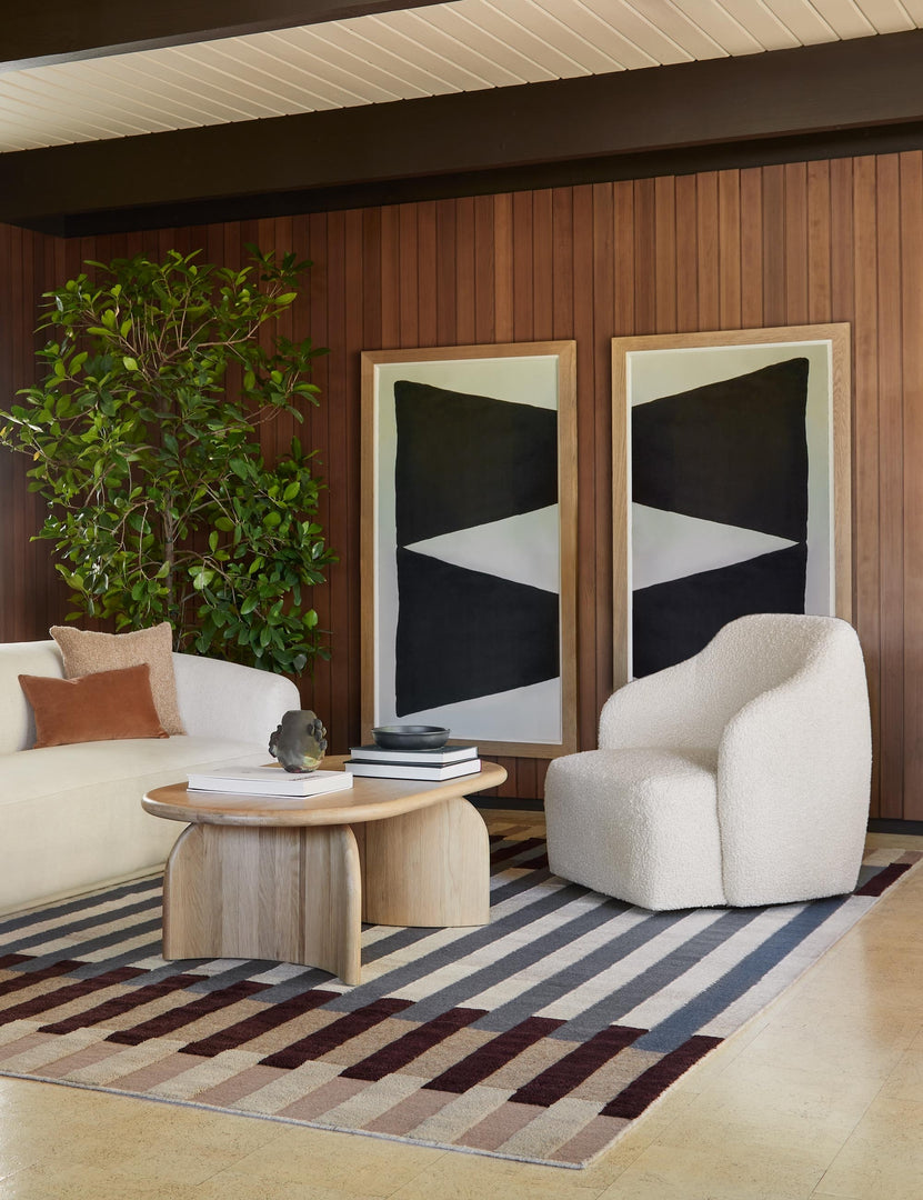 | The Sculpture I & II geometric two-toned prints sit in a retro living room against a wood paneled wall with boucle seating and a sculptural wooden coffee table in the foreground.