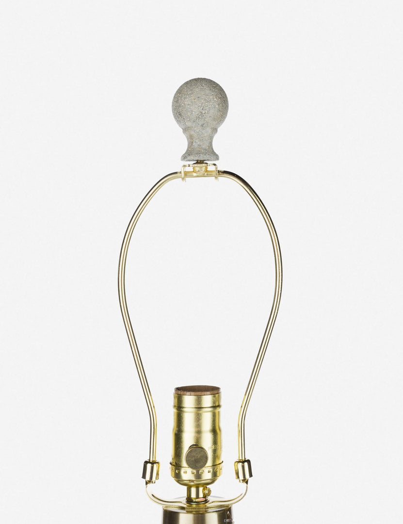 | Close-up of the golden lamp harp and light bulb insert on the Langley table lamp with stone base and white finial 